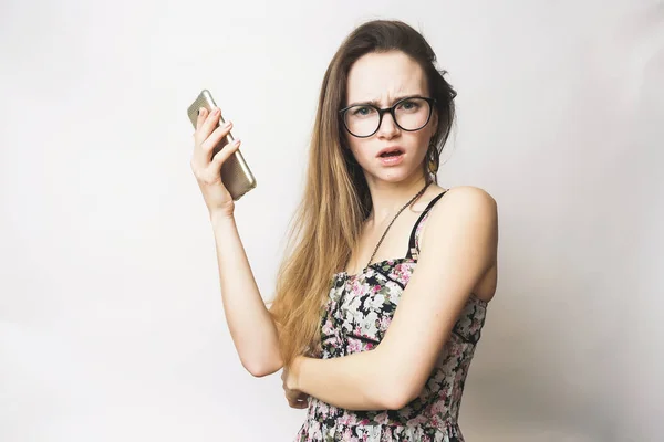 Escéptica mujer adolescente enojado utiliza móvil, con gafas y un vestido de moda —  Fotos de Stock