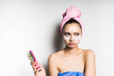 üzgün başında pembe havlu ile genç kız onun elinde tutan bir pembe saç tarak