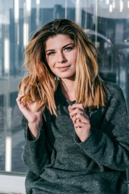 bir cam duvar tarafından poz şık bir bluz sevimli gülümseyen kız