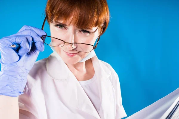 Intelligente medico donna adulta in occhiali e guanti blu guarda la fotocamera — Foto Stock