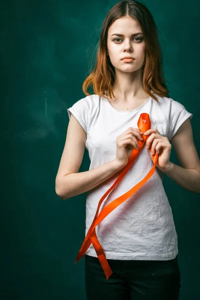 Jovem grave em uma camiseta branca segurando uma fita vermelha na forma de um símbolo — Fotografia de Stock