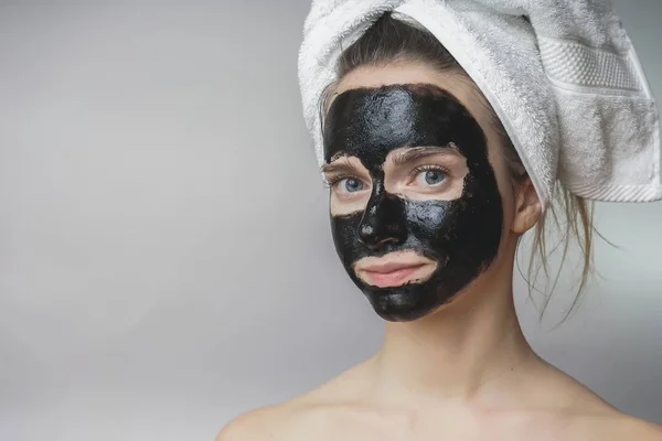 Mosolygós boldog nő alkalmazott skin care fekete mack face.moisturizer — Stock Fotó