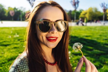 Komik gülümseyen mutlu kadın karahindiba üfleme güneş gözlüğü