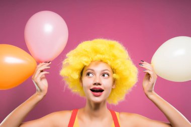 Bir palyaço kıyafetli mutlu bir kız onun elleri balonlar içinde tutar