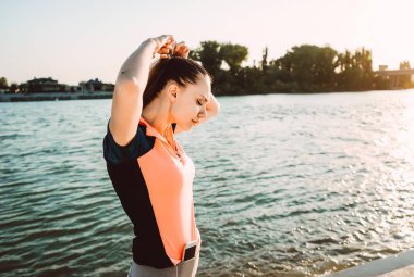 Sportif üniformalı bir kız saçını akşam koşu sırasında ayarlar