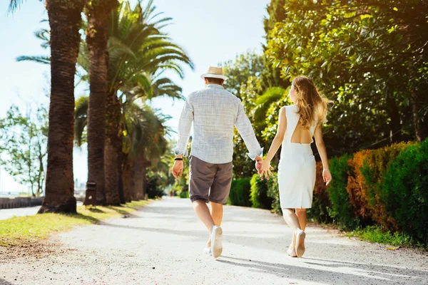 Um jovem casal está andando pela mão em um parque de verão — Fotografia de Stock