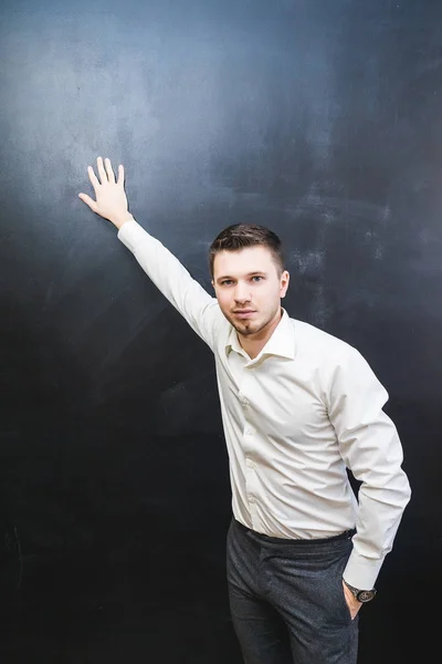 Giovane uomo in camicia da lavoro si appoggia contro un muro nero — Foto Stock