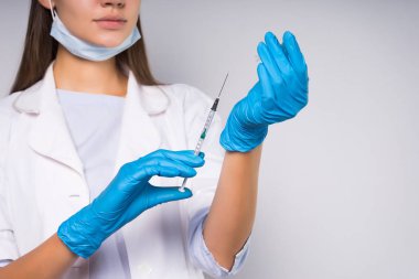 Beyaz tıp sabahlık, mavi eldiven genç kadın doktor ilaç şırınga tutar