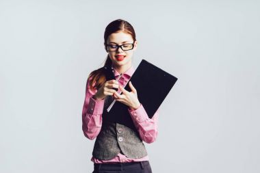 Gözlüklü şık genç kadın, pembe gömlek gülümseyen ve aşağı bakıyor belgeleri, tutuyor