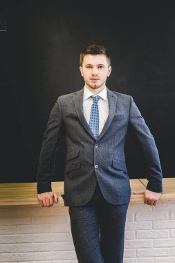 elbiseli sağlam bir genç adam blackboard standları ve doğrudan kameraya benziyor