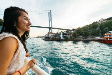 Gün batımında, bir yat olumlu kız seyahatlerinizde inceliyor manzaraları, boğaz üzerinde modern köprü