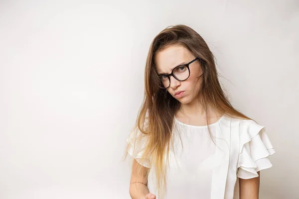 Smutný naštvaný dívka v brýlích a bílé sako vypadá do kamery a vypadá nespokojen — Stock fotografie