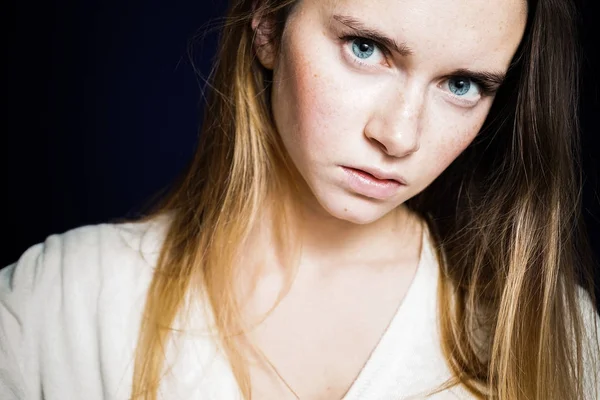Trauriges junges Mädchen mit blauen Augen, in weißer Jacke blickt in die Kamera — Stockfoto