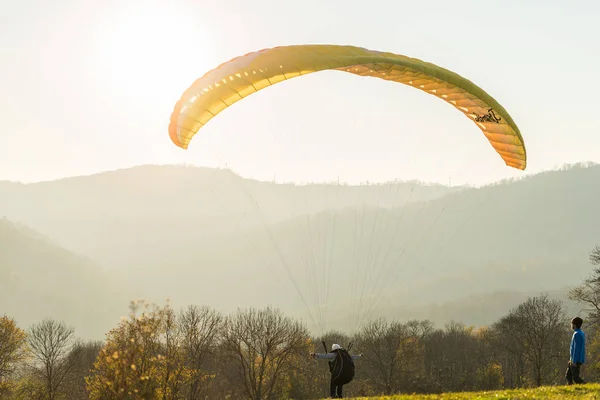 El tipo está volando en un paracaídas amarillo. naturaleza hermosa salvaje, tiempo soleado, vista a la montaña — Foto de Stock