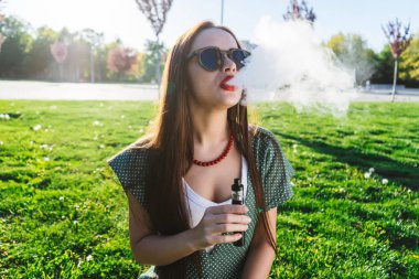Mutlu moda gülümseyen kadın güneş gözlüğü vape Street, duman Sigara