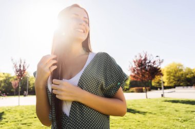 Gülümseyen kadın hayattan zevk ve yaz, parkta yeşil çim yürür