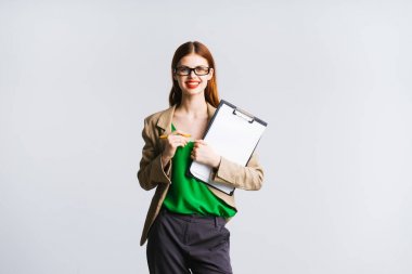 Kızıl saçlı başarılı kız gözlük ve yeşil bir ceket belgeleri elinde gülümsüyor tutar.