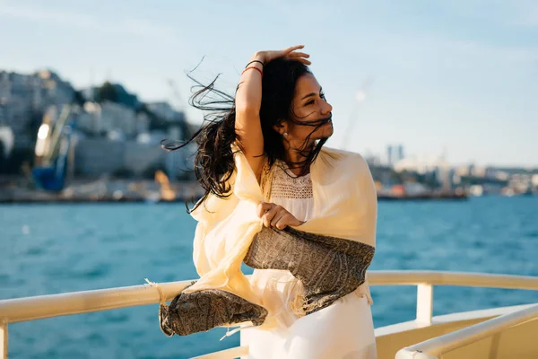 Felice ragazza sorridente su una barca godendo il tramonto, il sole, avvolto in una sciarpa — Foto Stock