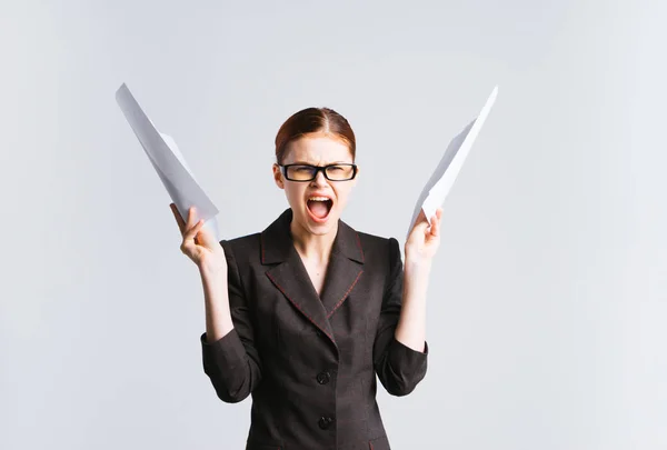 Ein wütendes nervöses Mädchen mit Brille und schwarzem Anzug hält Dokumente in den Händen und schreit, ist unzufrieden mit dem Geschäft — Stockfoto