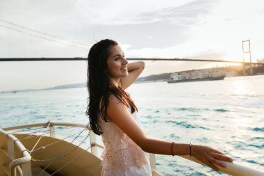 Bir genç kız gezgin bir yat gezisi sırasında rahatlatır, saçlarını düzeltiyor, gün batımını sahiptir