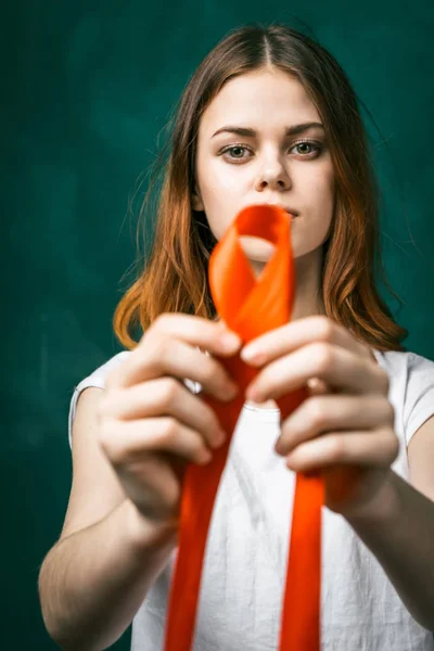 Linda menina faz um laço de fita vermelha-laranja. fita de close-up — Fotografia de Stock