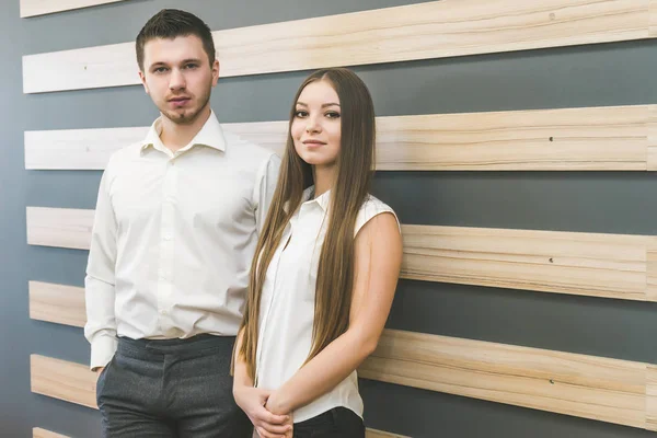 Belo casal cara e menina stand no escritório perto da parede e olhar para a câmera — Fotografia de Stock