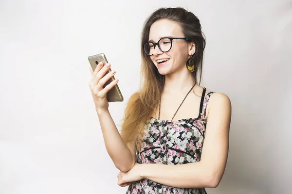 Felice adolescente sorridente cercando qualcosa in cellulare. Ragazza in occhiali — Foto Stock