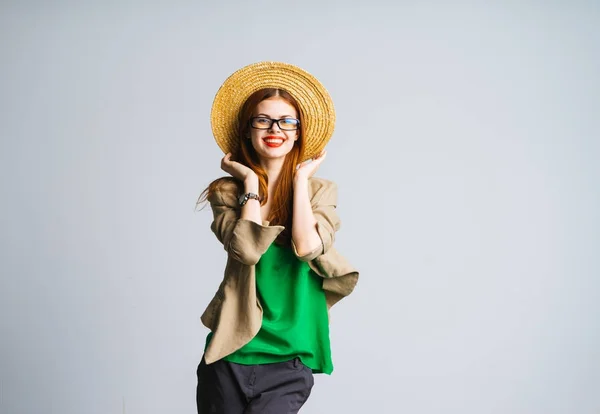 Κορίτσι σε ένα καπέλο και μια πράσινη μπλούζα και γυαλιά, γέλια και εξετάζει τη φωτογραφική μηχανή, με μόνωση — Φωτογραφία Αρχείου