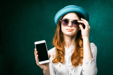 Güneş gözlüğü Mavi şapkalı bir kız telefonu elinde tutuyor