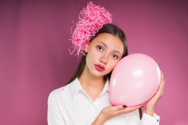 Sinirli bir kız pembe bir arka plan üzerinde pembe boncuk gösterir