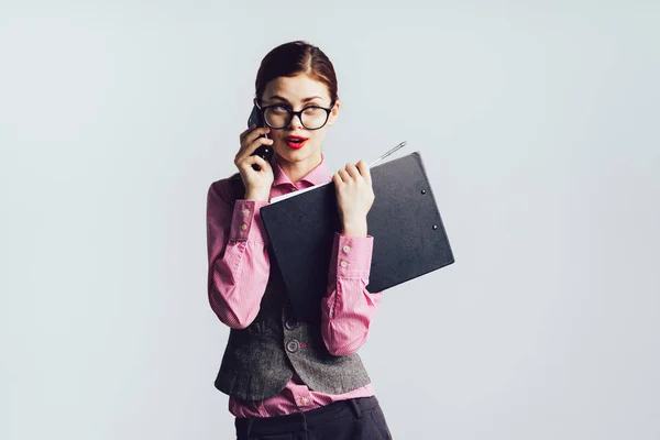Sekretärin mit Brille hält eine Mappe in der Hand und telefoniert — Stockfoto