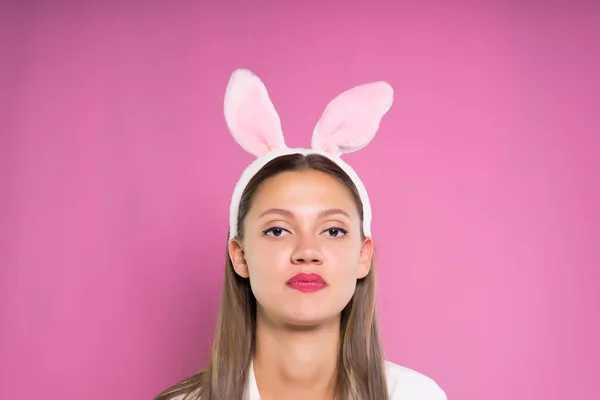 O fată dezamăgită în urechi de iepure pe un fundal roz — Fotografie, imagine de stoc