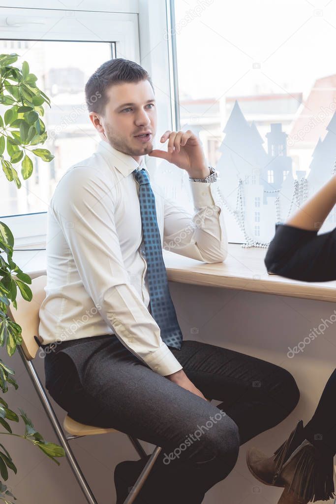 Young man in a business shirt talking with his colleague