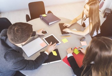 Ofis çalışanları bir grup bir yuvarlak masaya oturmak ve çalışma sorunlarını tartışmak. Tablo yalan kağıtlara kalemler, dergi, tablet