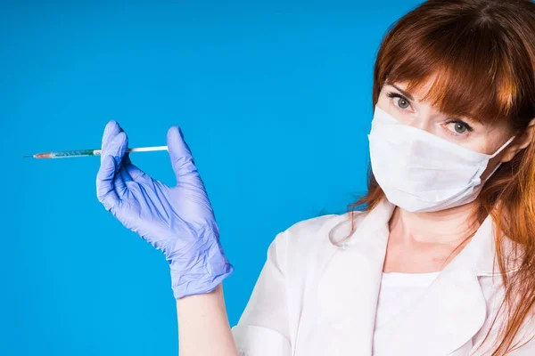 Niña enfermera en una máscara y con guantes sostiene una jeringa en sus manos y va a hacer que alguien un tiro aislado — Foto de Stock