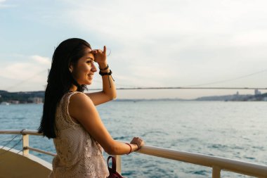 Bir kız günbatımında denizde, mesafe, Boğaz'ın bir köprüden bir şey arıyor görünüyor