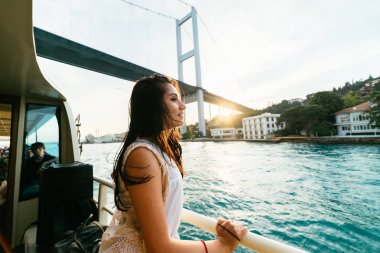 Genç özgürlük mutlu kız gün batımında tekne modern köprü altında seyahat