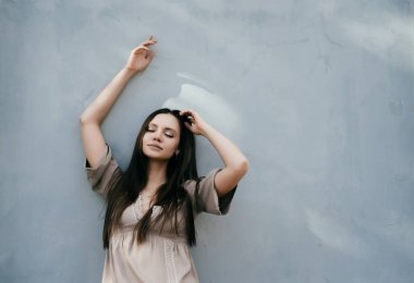 Duvar tarafından ayakta ve gözleri kapalı poz uzun saçlı kız