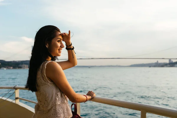 Девушка смотрит на закат в море, ищет что-то вдалеке, мост через Босфор — стоковое фото