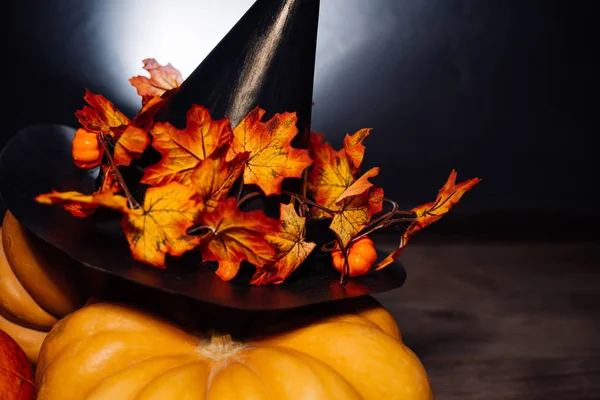 Podzimní prázdniny, velké dýně, zlaté listy na černé čarodějnice klobouk. Halloween, okouzlující obrázek — Stock fotografie