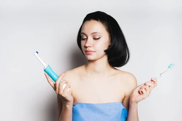 Девушка с короткими черными волосами выбирает, какую щетку чистить зубы, выделенные на белом фоне — стоковое фото