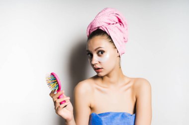 Kafasındaki bir pembe havlu ile sürpriz genç kız bir tarak onun elinde tutar.