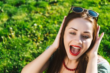 Gözlük, güneş gözlüğü, sürpriz komik surat kadınla parkta yeşil çim oturur