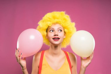 sevimli genç kız sarı palyaço peruk ile onun elinde tutan başında havadar bir çok renkli, gülümseyen balonlar