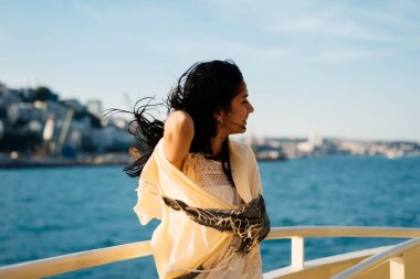 Tekne Istanbul, saçında güçlü bir rüzgar şehirde arka planı ile garip bir kız bir Fularlı yüzüyor