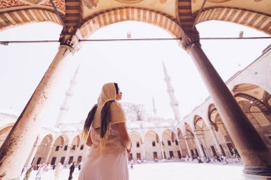 Kafasına eşarp genç kadın Gezgin ile geri Sultanahmet Camii arka plan üzerinde duruyor. Yaz tatillerinde seyahat