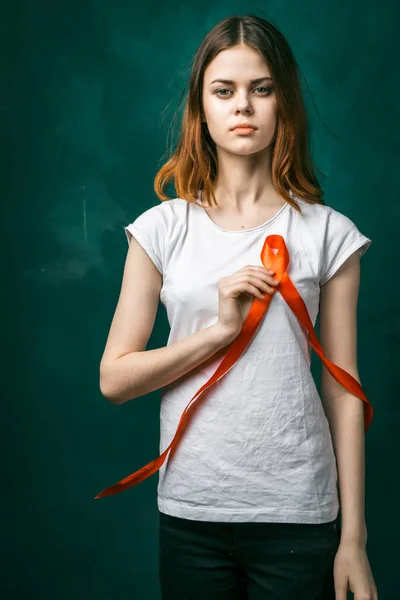 Jovem grave em uma camiseta branca segurando uma fita vermelha na forma de um símbolo — Fotografia de Stock