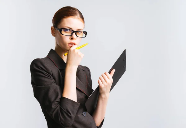 Серьезная молодая девушка в очках и черном строгом костюме думает о работе, смотрит в камеру — стоковое фото