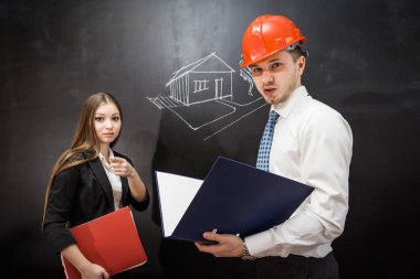 yazı tahtası resmi evi olan genç kendine güvenen kız ve adam builder turuncu bir koruyucu kask içinde durmak