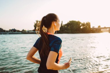 Güneşin nehir set boyunca kaçan uzun saçlı fitness kız